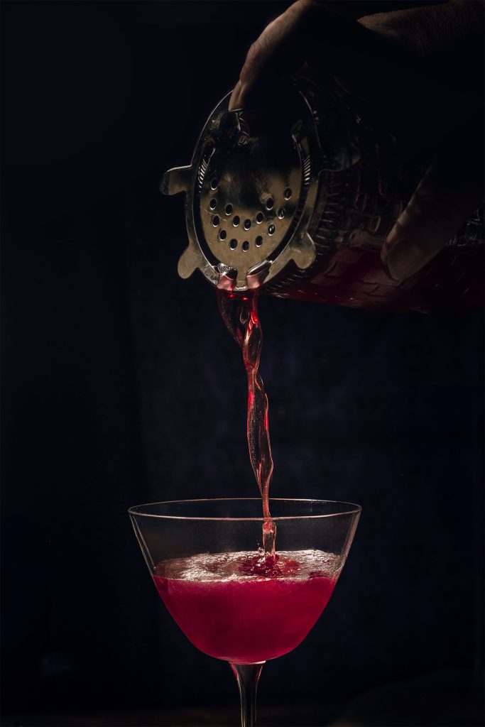 Dramatic red cocktail pour with smoke and candlelight, creative cocktail photography by Lou Carruthers UK drinks photographer