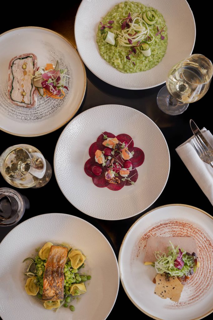 Overhead view of multiple plated courses served with wine glasses during a private dining experience at Siddington Park, photographed by Lou Carruthers, Lou Carruthers Photography, Hospitality & Drinks Photographer, Cotswolds and Menorca