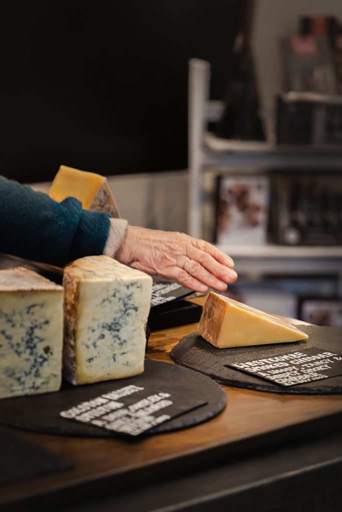 Hand-cut artisan cheese at Corn Hall Deli, Cirencester — food and product photography by Lou Carruthers