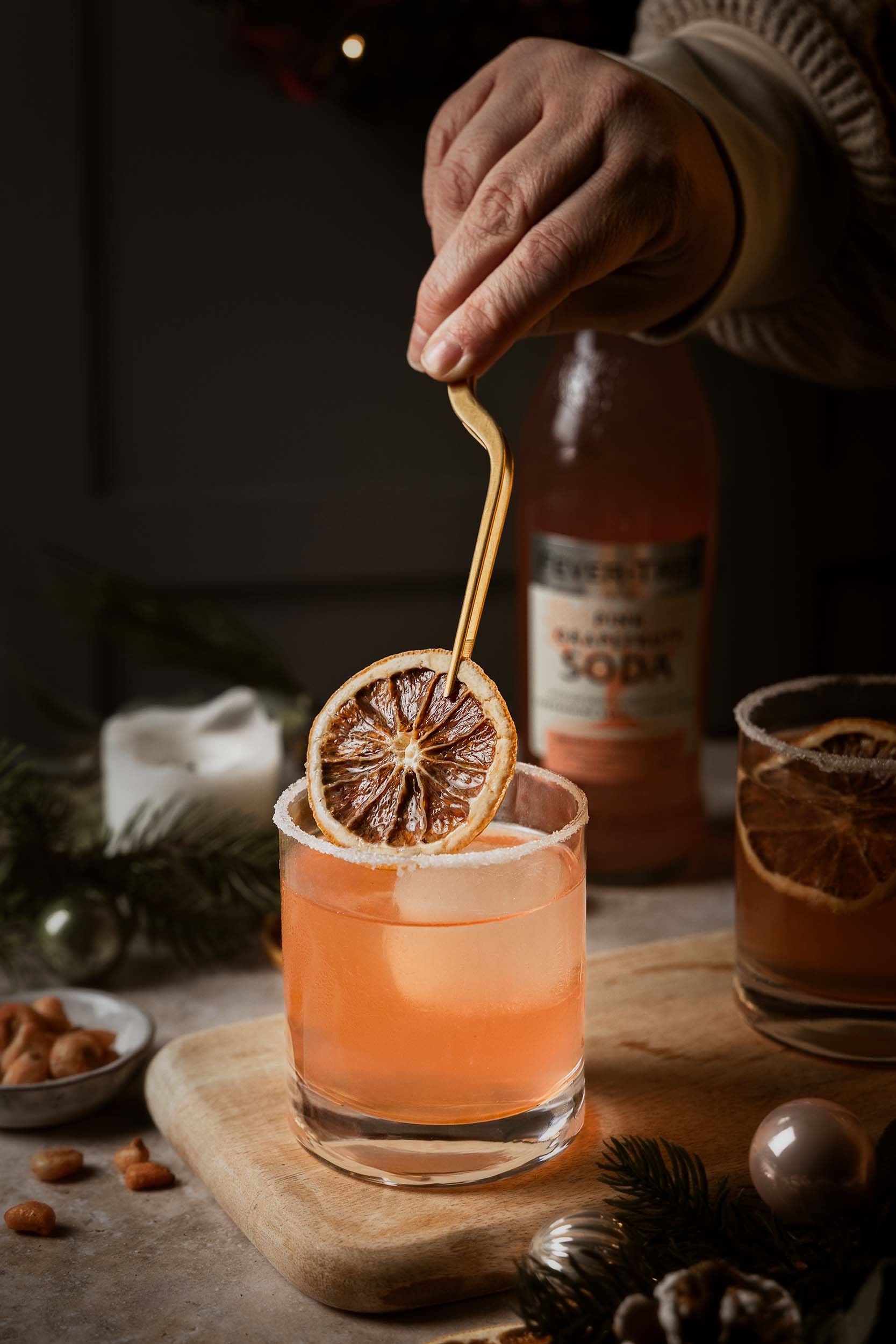 Festive Paloma cocktail with Fever-Tree Pink Grapefruit Soda, garnished with dried orange and served on a winter-themed table setting by Lou Carruthers Photography