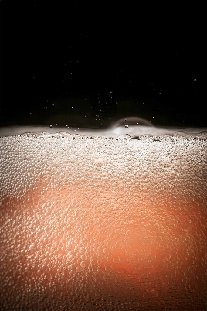 Macro close-up of carbonation bubbles in pink grapefruit cocktail showing texture and detail, drinks photography by Lou Carruthers