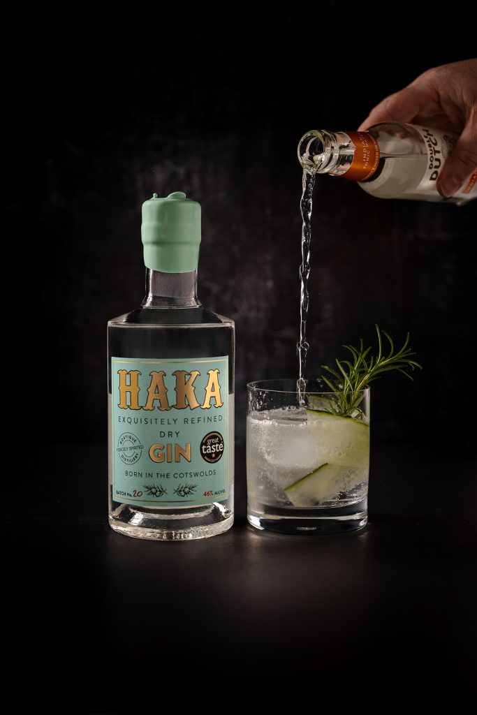 Hand pouring Haka Gin into garnished glass, action drinks photography by Lou Carruthers UK spirits photographer