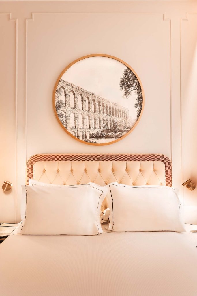 Hotel bedroom at H10 Palazzo Galla in Rome, featuring a softly lit upholstered headboard, crisp white linens and a circular artwork depicting Roman arches above the bed. Shot by Lou Carruthers Photography, Hospitality and Drinks Photographer, Cotswolds and Menorca